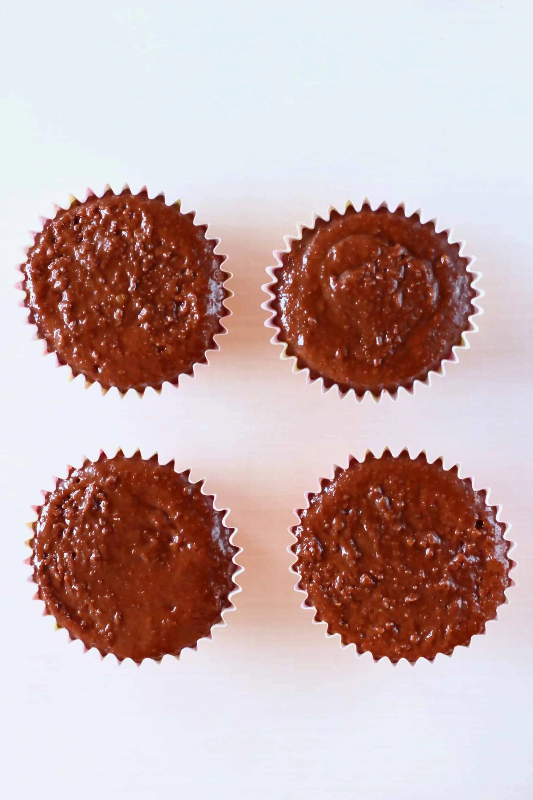 Four cupcake cases filled with raw gluten-free vegan chocolate cupcakes batter