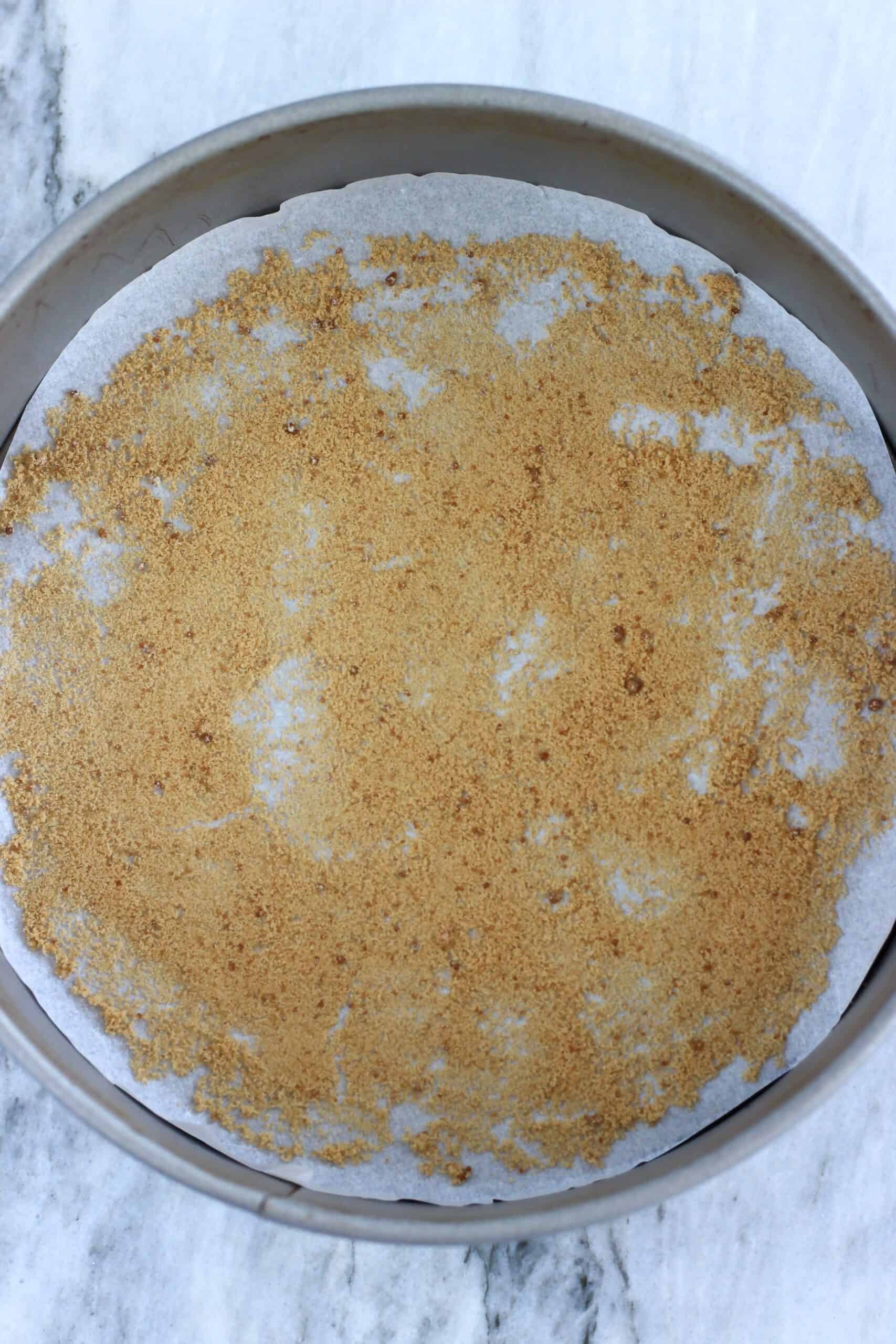 A round springform baking tin lined with baking paper sprinkled with coconut sugar