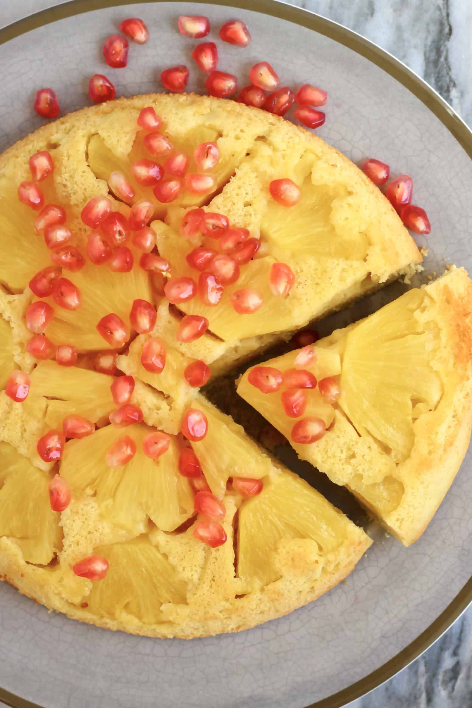 Gluten-free vegan pineapple upside down cake on a plate with a slice cut out of it