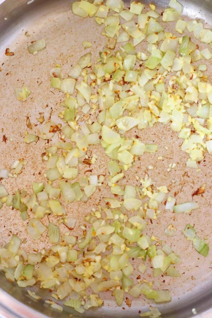 Photo of diced onion being fried in a silver saucepan