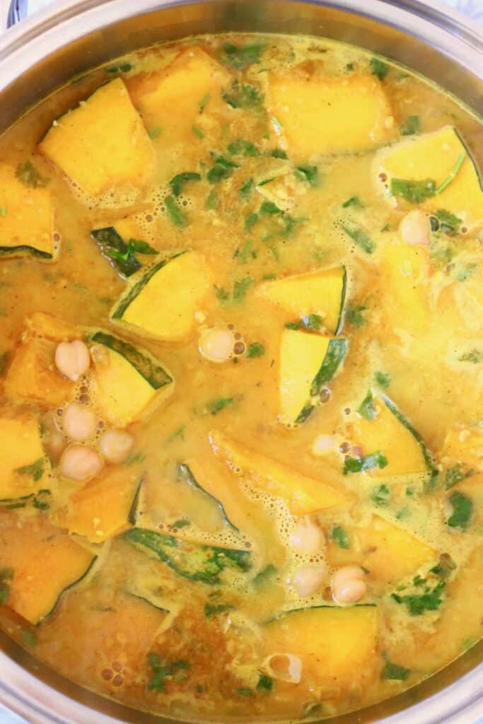Photo of diced pumpkin, chickpeas and coriander in a yellow curry sauce in a silver saucepan