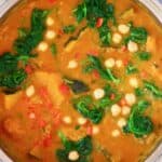Photo of diced pumpkin, chickpeas and spinach in a yellow curry sauce in a silver saucepan