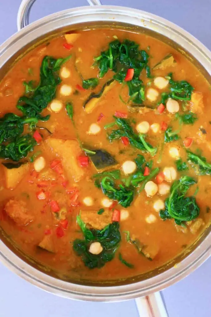 Photo of diced pumpkin, chickpeas and spinach in a yellow curry sauce in a silver saucepan