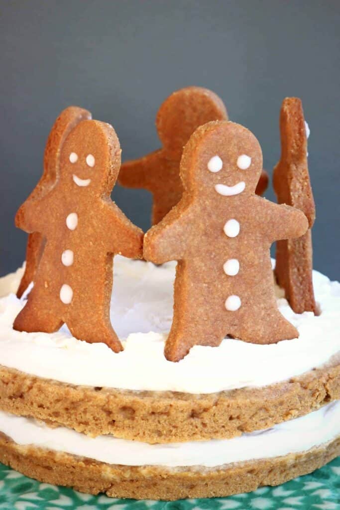 Photo of gingerbread sponge cake sandwiched with white cream topped with five gingerbread men cookies standing in a circle