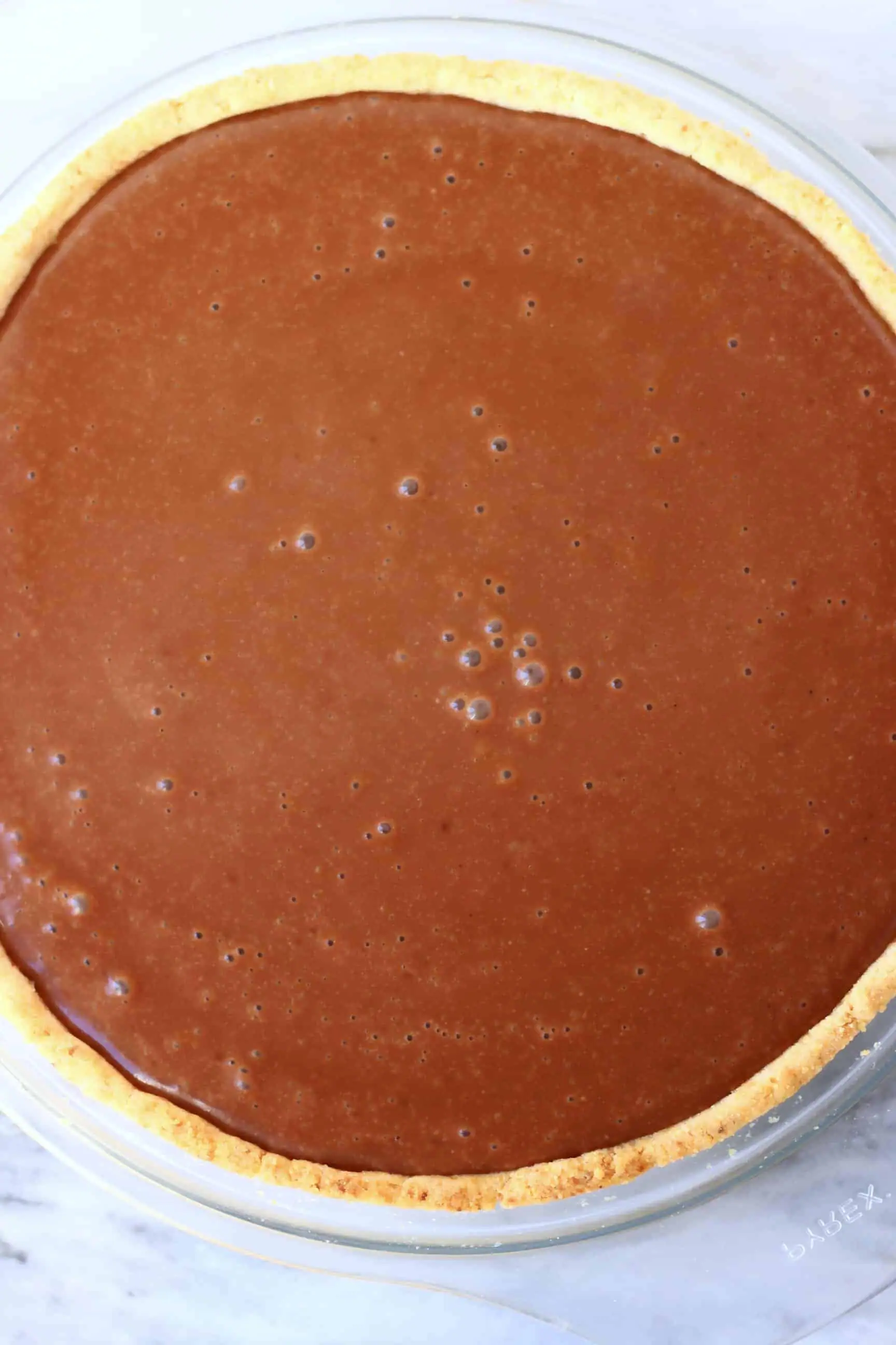 A pastry tart crust in a pie dish filled with vegan chocolate custard 