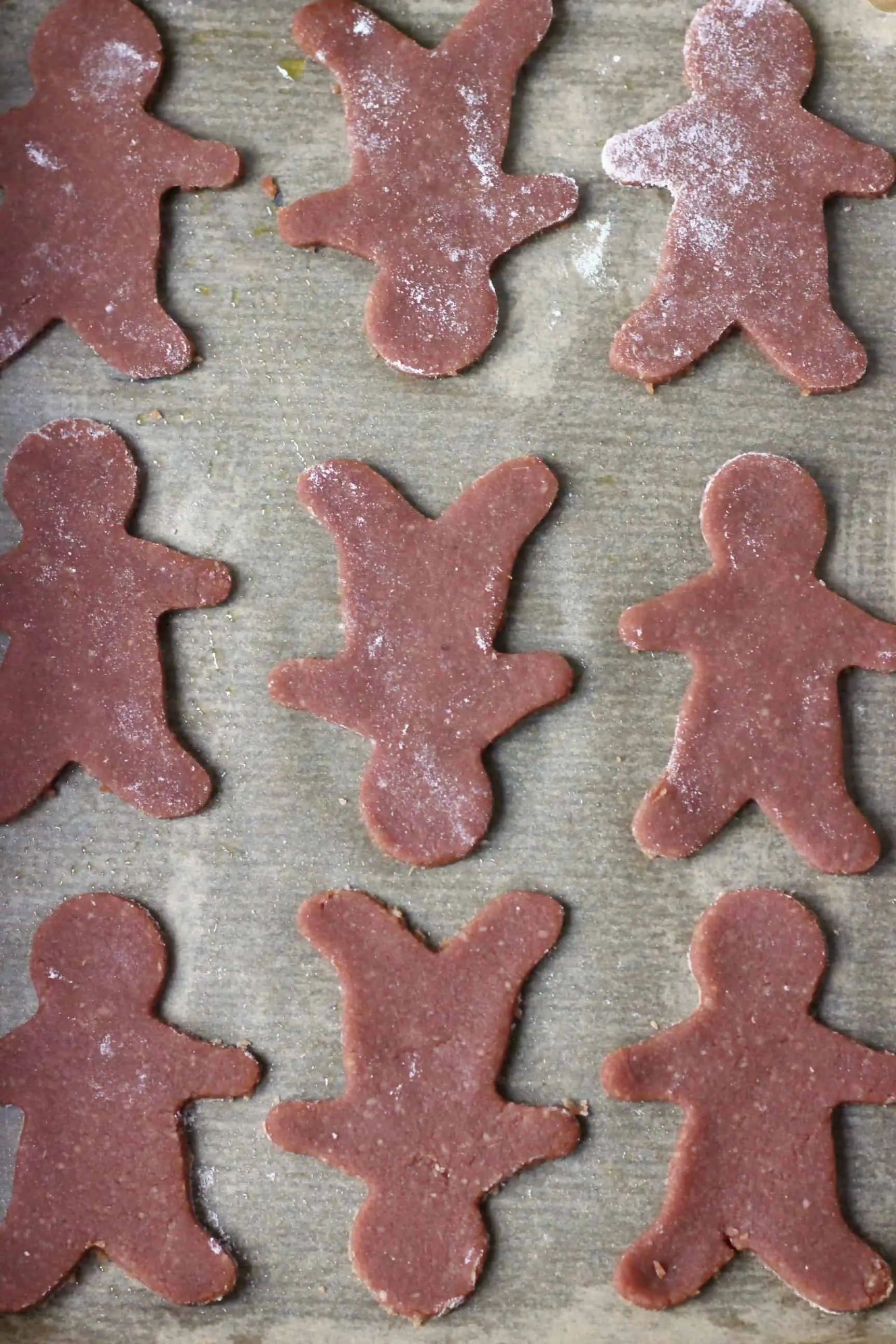 Nine raw gluten-free vegan gingerbread cookies on a sheet of baking paper