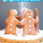 Photo of gingerbread sponge cake sandwiched with white cream topped with five gingerbread men cookies standing in a circle with a dusting of white icing sugar