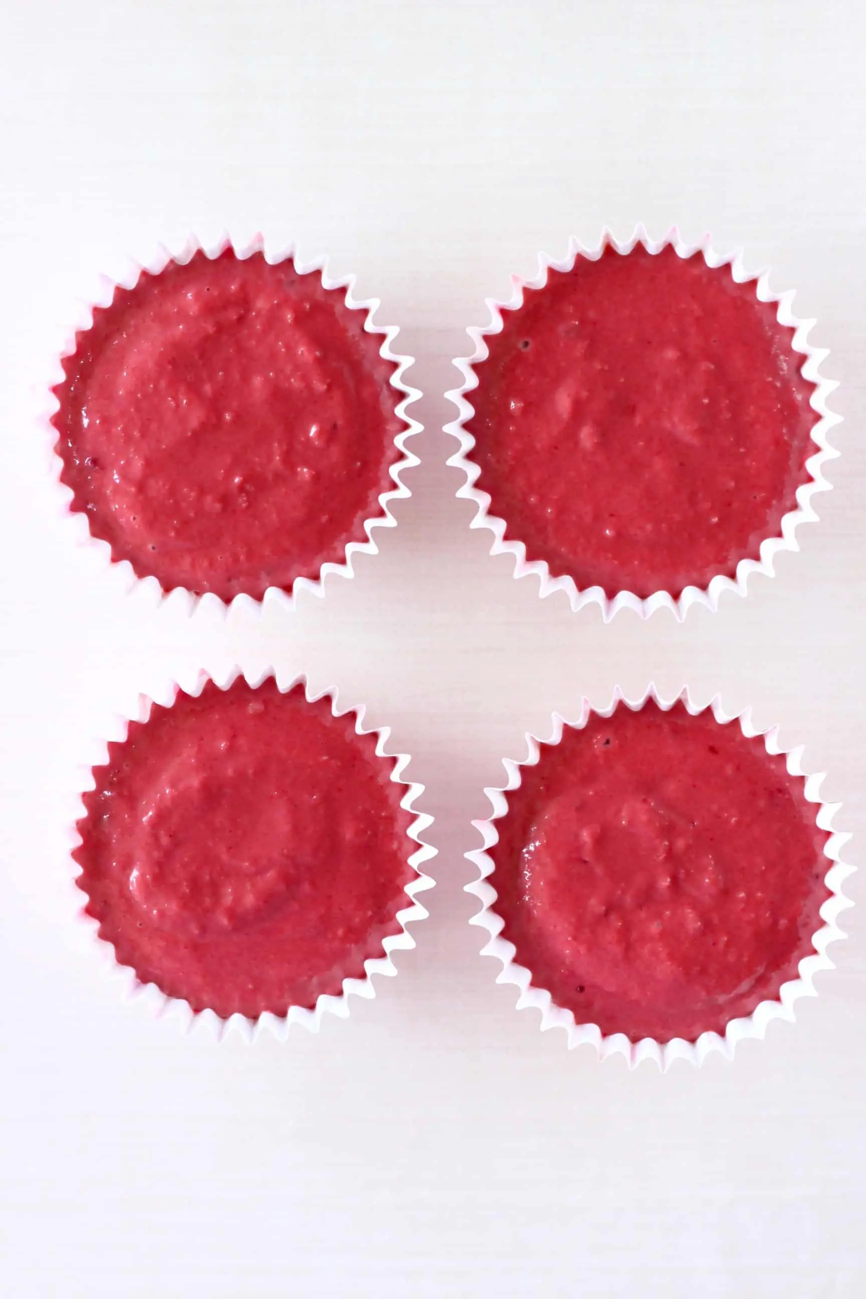 Four cupcake cases filled with raw gluten-free vegan red velvet cupcakes batter 