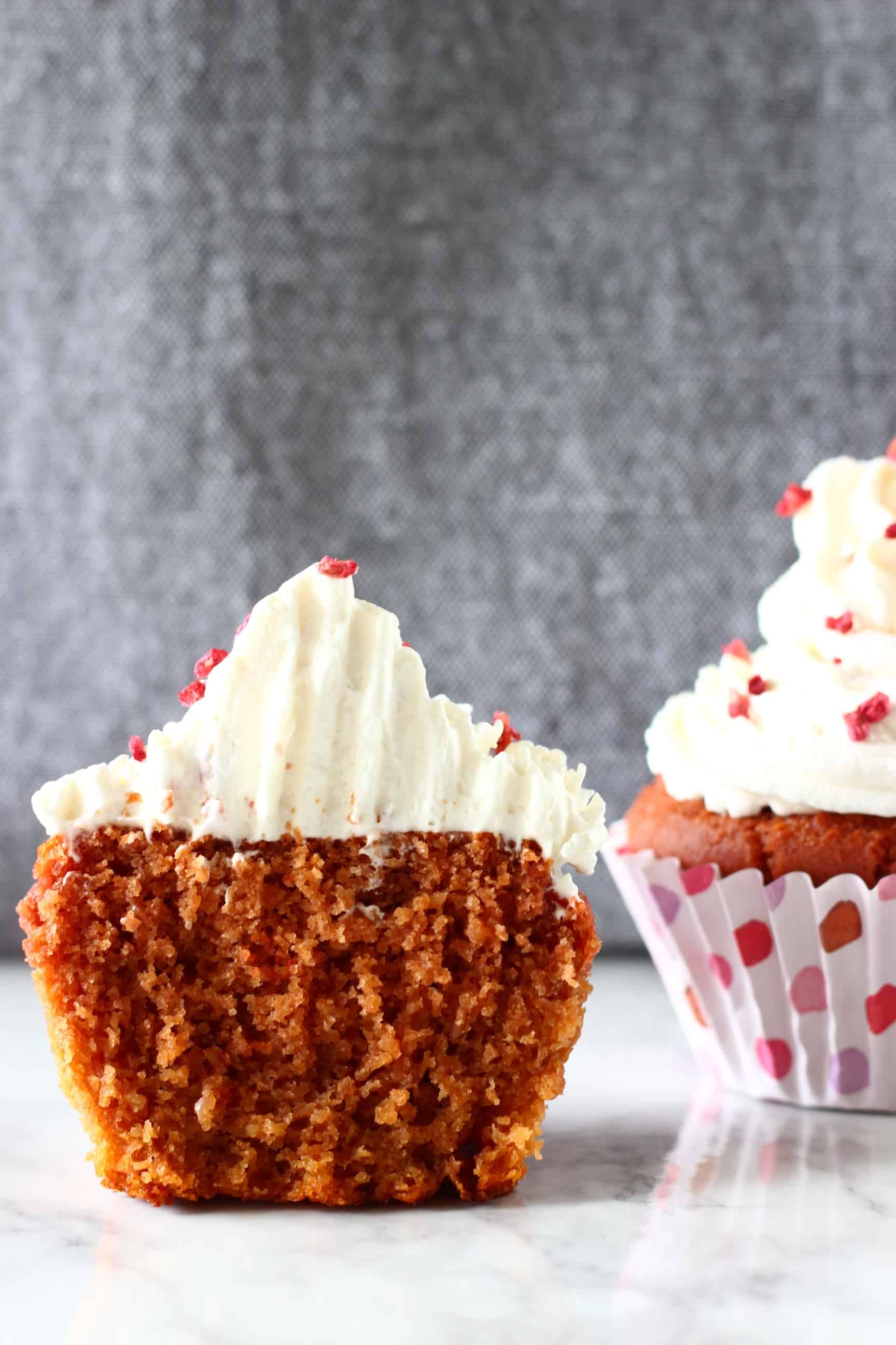 A halved gluten-free vegan red velvet cupcake topped with cream cheese frosting