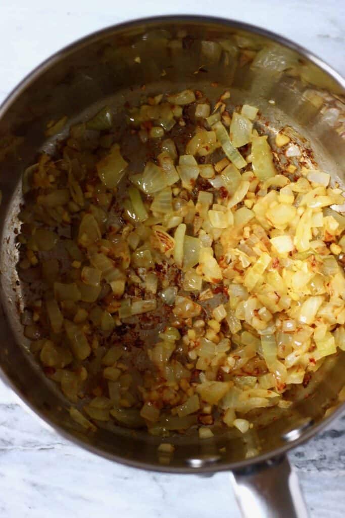 Photo of diced onions being fried in a silver saucepan