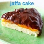 A slice of sponge cake topped with chocolate ganache on a green plate