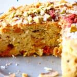 Photo of fruit cake on a grey plate with a slice taken out of it