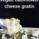 Photo of cauliflower and broccoli cheese gratin taken from the side with a spoon lifting up a mouthful of it