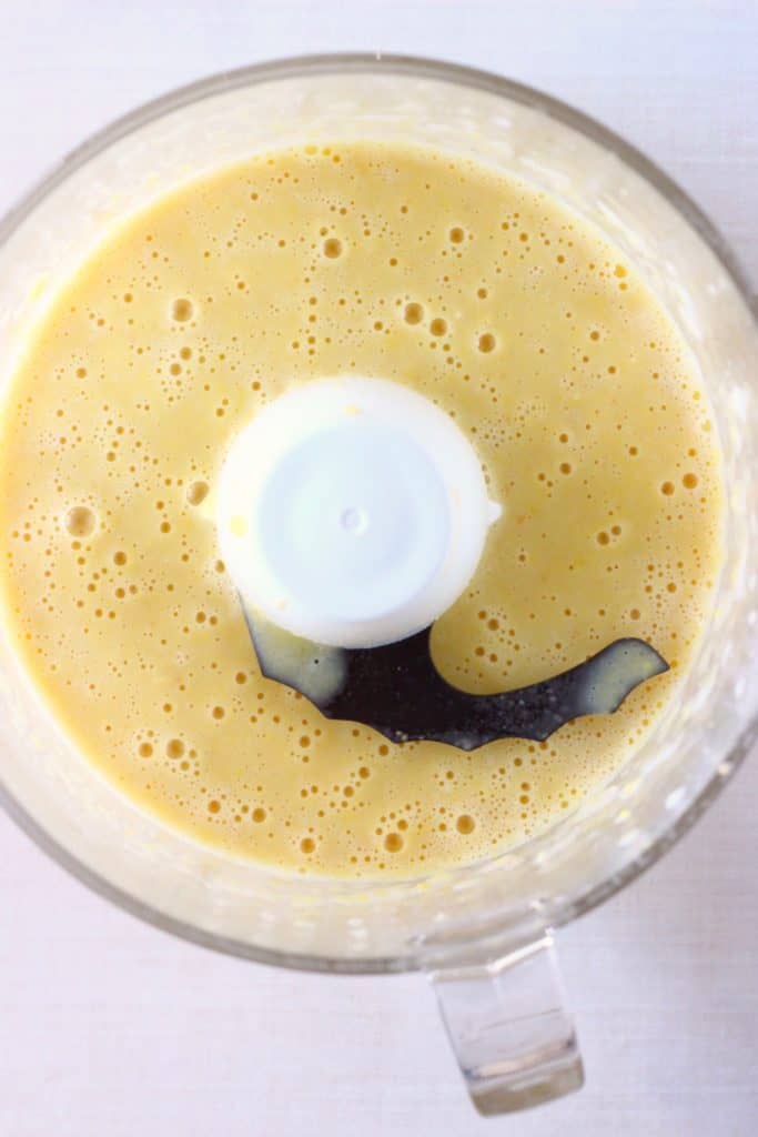 Yellow sweetcorn soup in a food processor against a white background