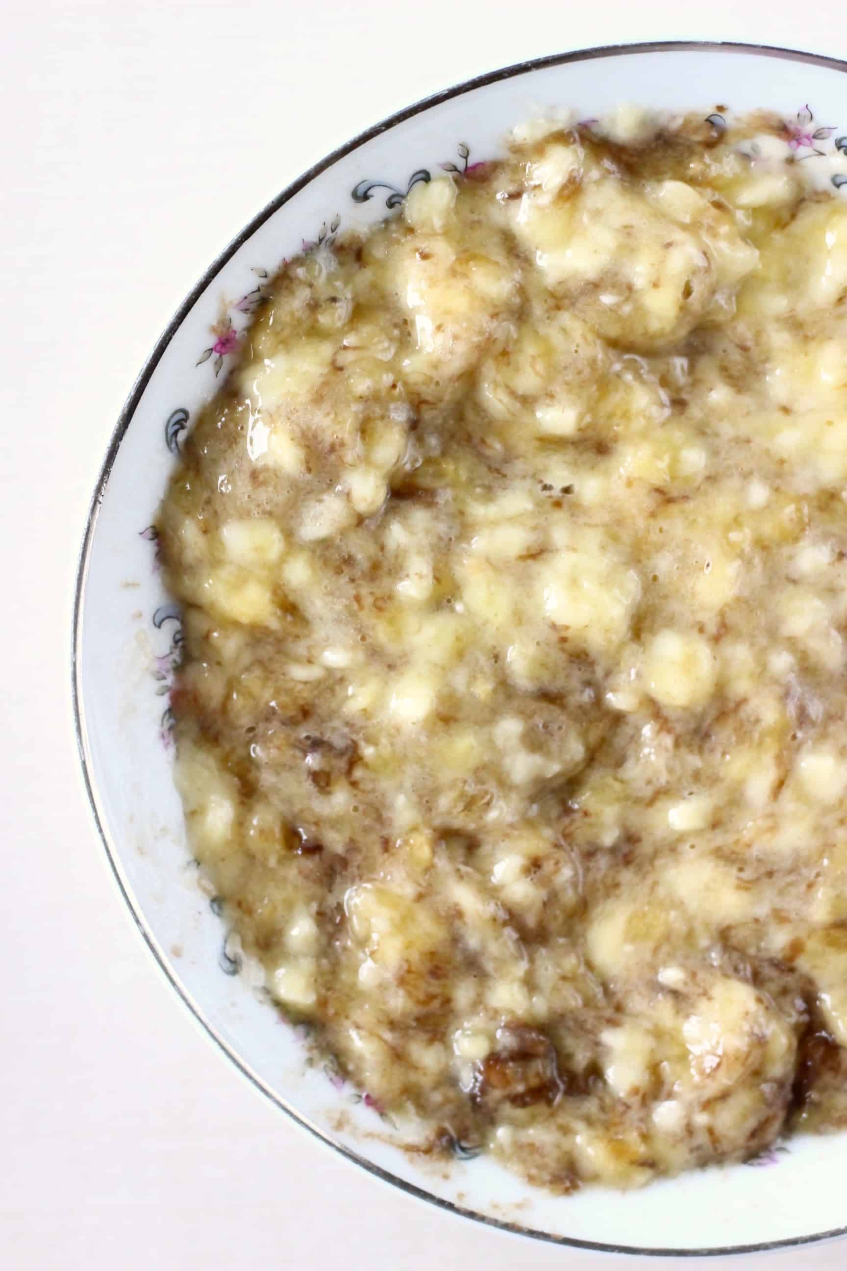 Mashed bananas in a white bowl against a white background