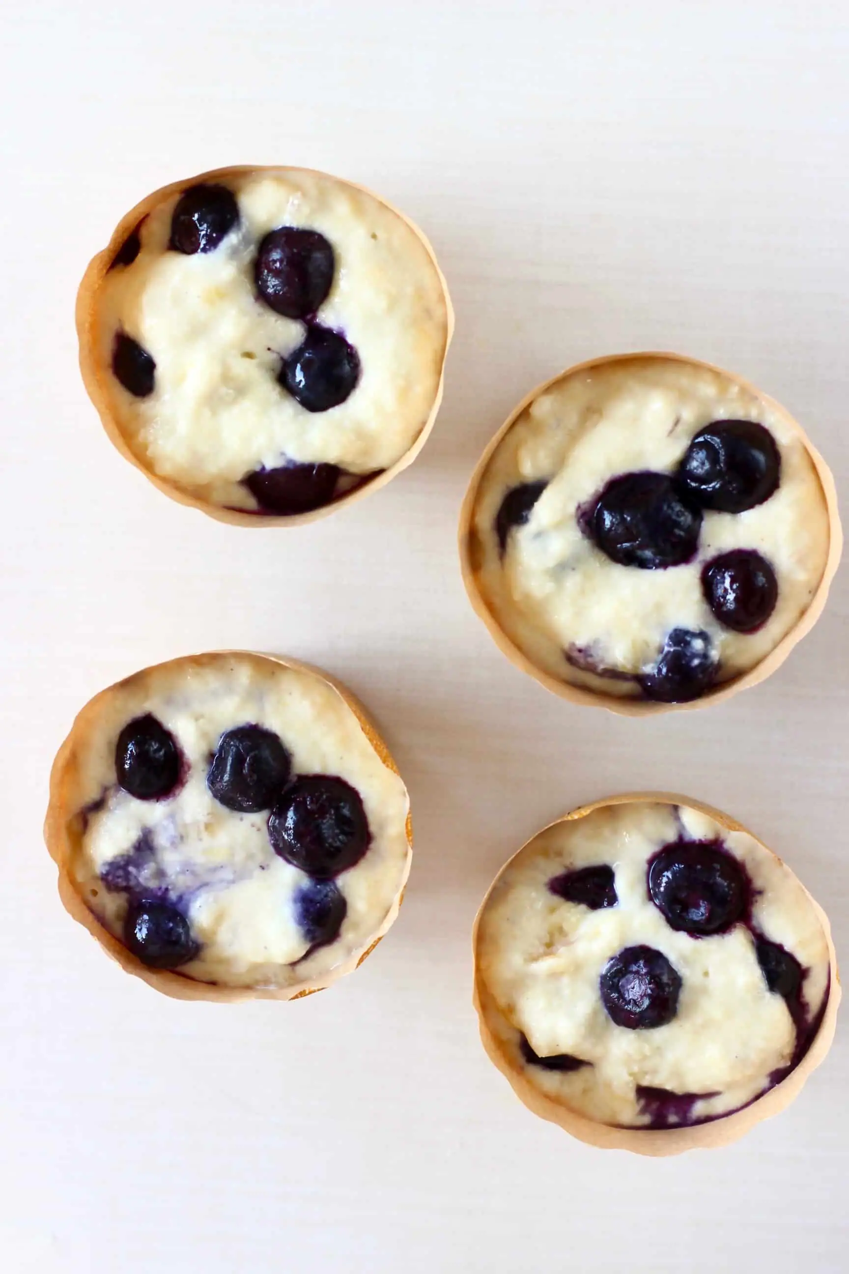 Four muffin cases filled with vegan blueberry muffin batter