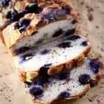 A loaf of gluten-free vegan blueberry banana bread with three slices cut from it