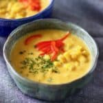 Two bowls of corn chowder against a grey background