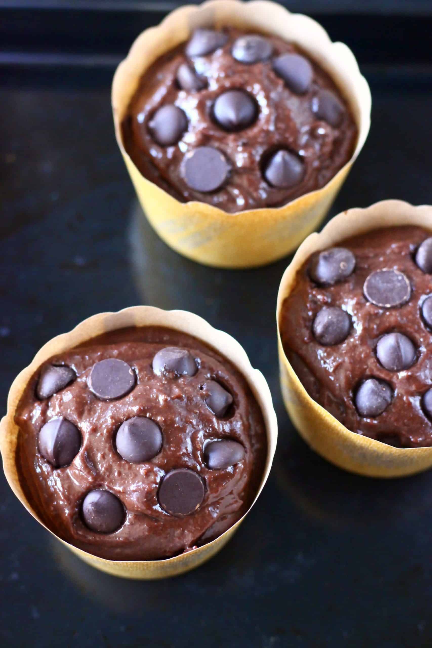 Raw gluten-free vegan chocolate muffins batter in brown muffin cases topped with chocolate chips