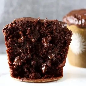 Two gluten-free vegan chocolate muffins with chocolate chips, one cut in half