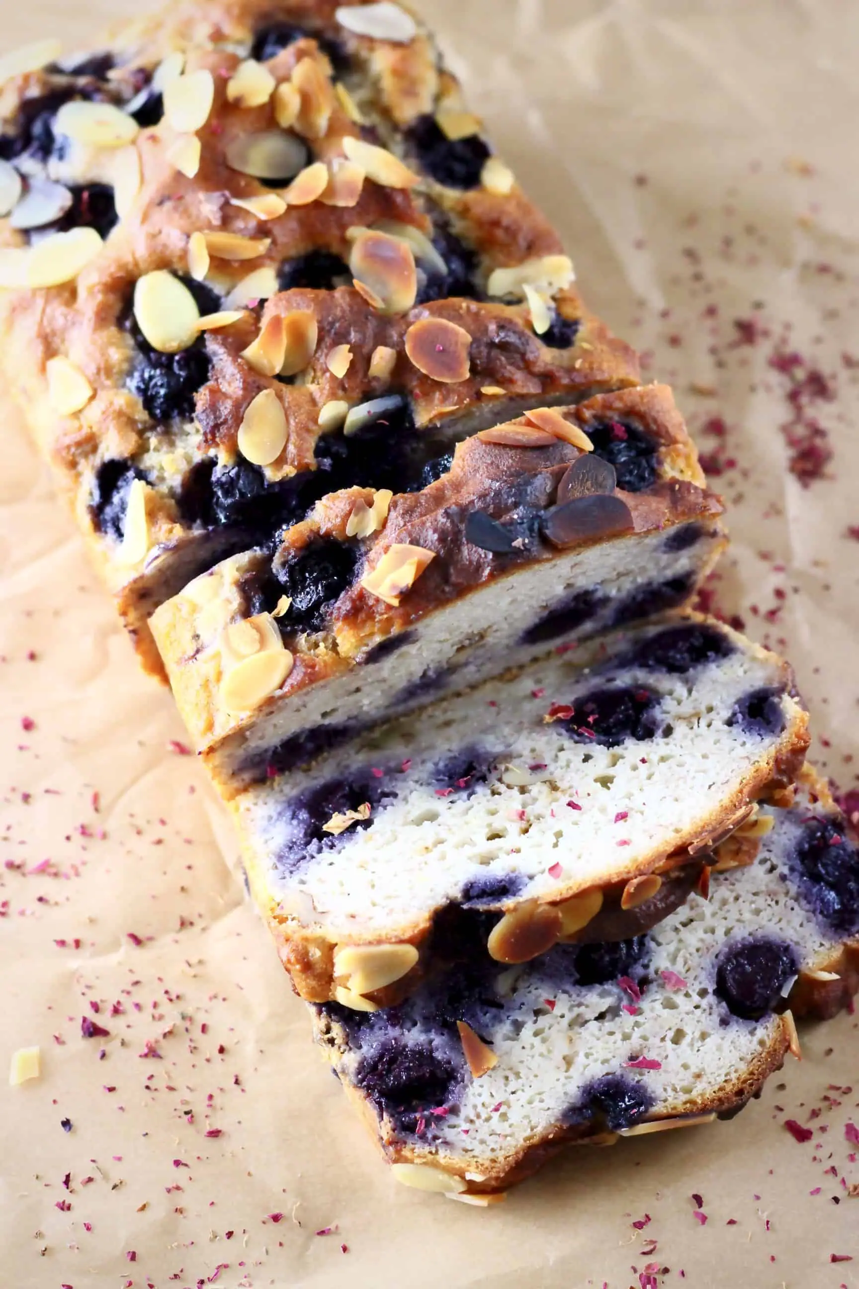 A loaf of gluten-free vegan blueberry banana bread with three slices cut