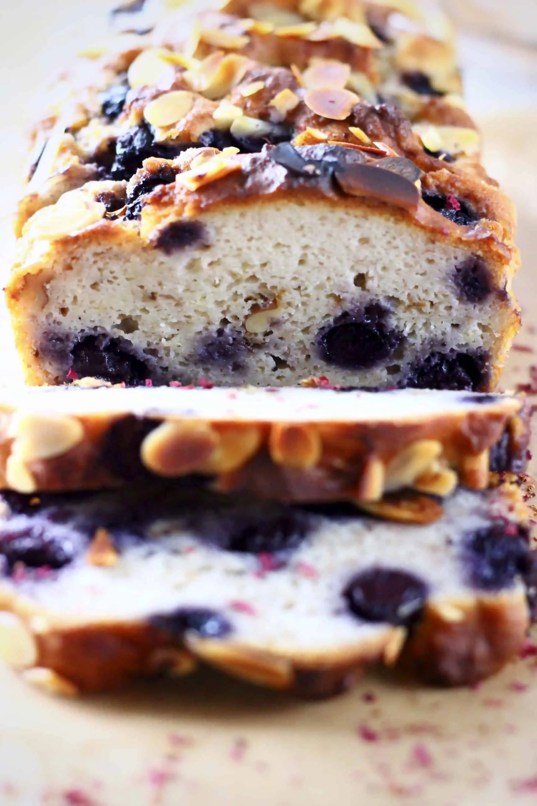 A loaf of gluten-free vegan blueberry banana bread with three slices cut