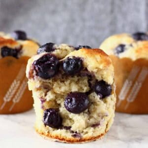 Three gluten-free vegan blueberry banana muffins with one cut in half