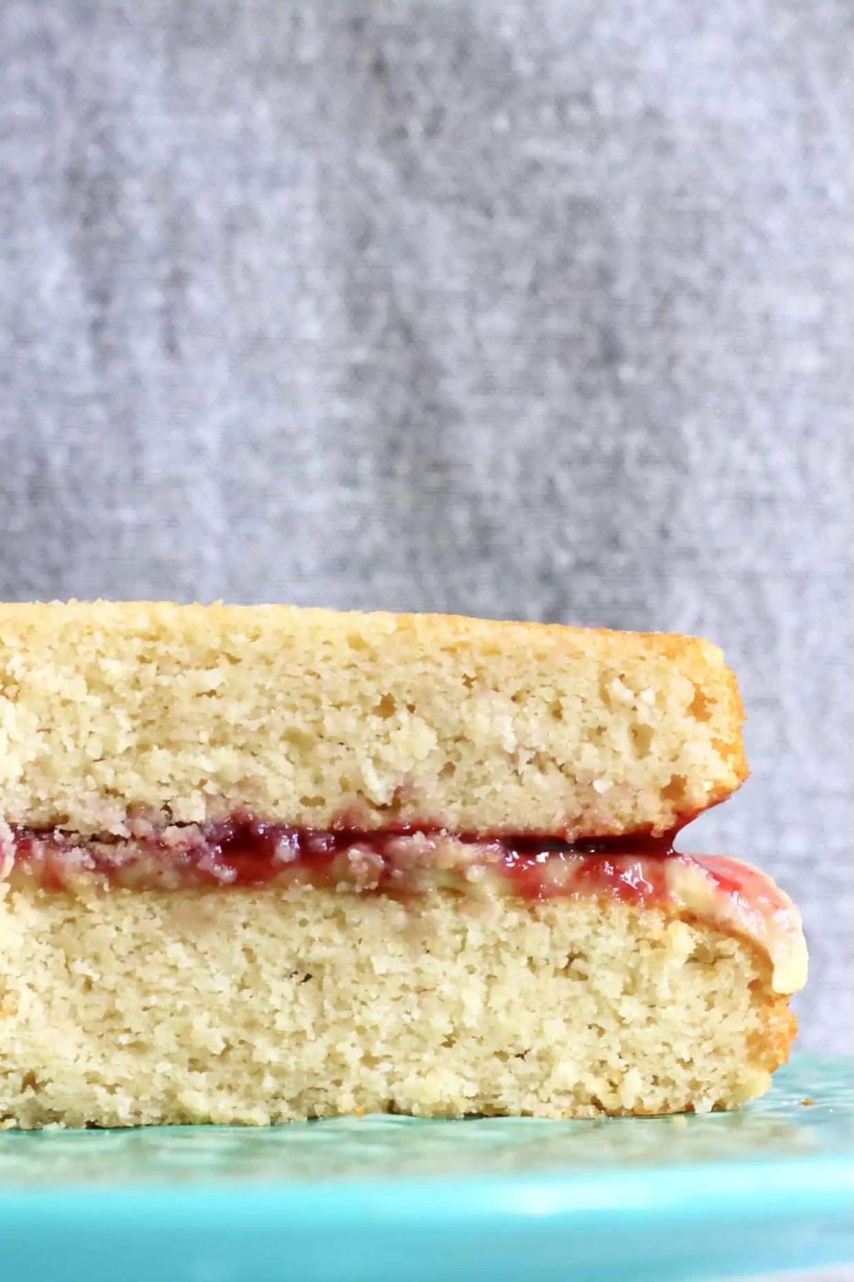 A sliced gluten-free vegan Victoria sponge cake with buttercream and raspberry jam