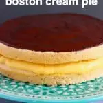 A Boston cream pie on a green cake stand against a grey background
