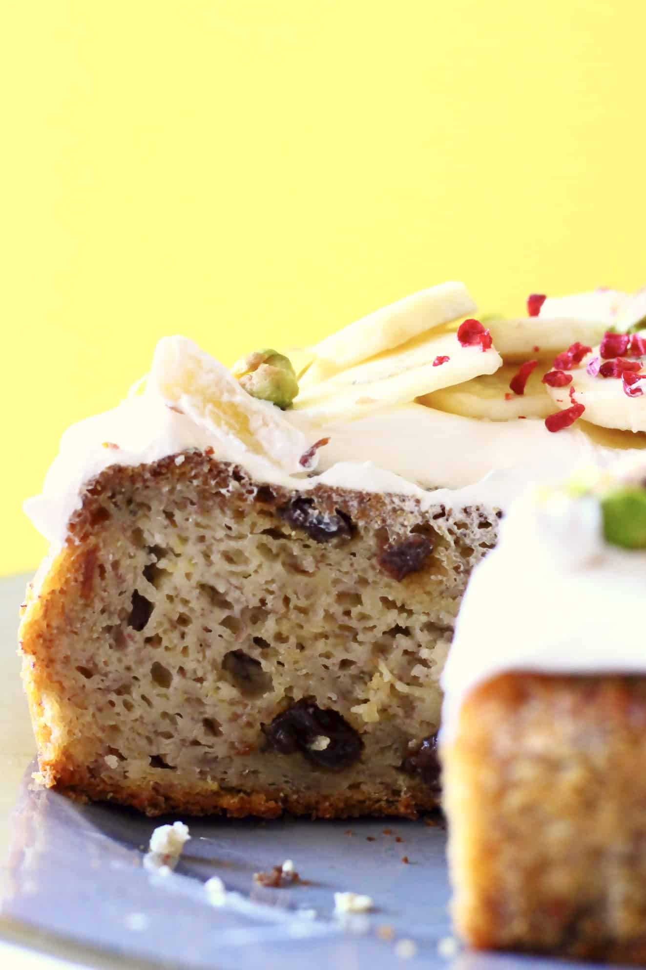 Sliced banana cake with raisins topped with white frosting and sliced bananas