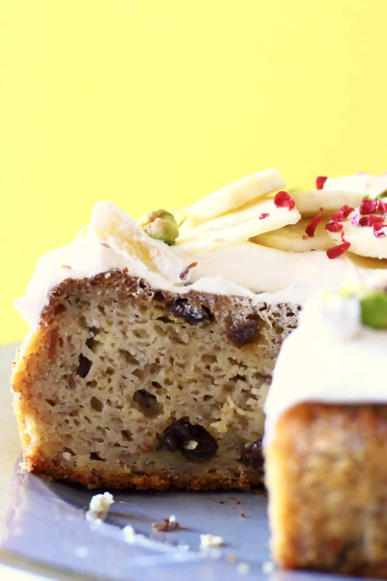 Sliced banana cake with raisins topped with white frosting and sliced bananas
