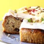 Sliced banana cake with raisins topped with white frosting and sliced bananas