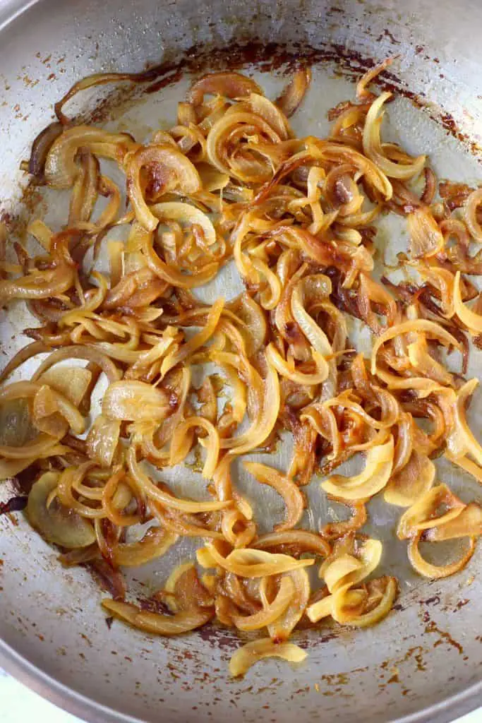 Brown caramelised onion slices in a silver frying pan