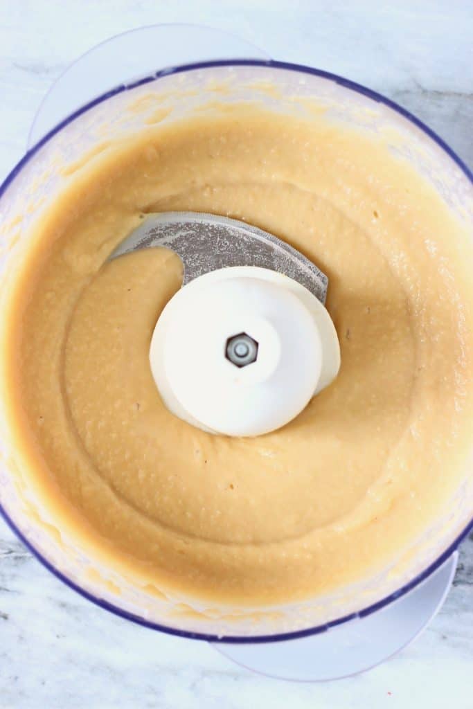 Creamy white dip in a food processor against a marble background 