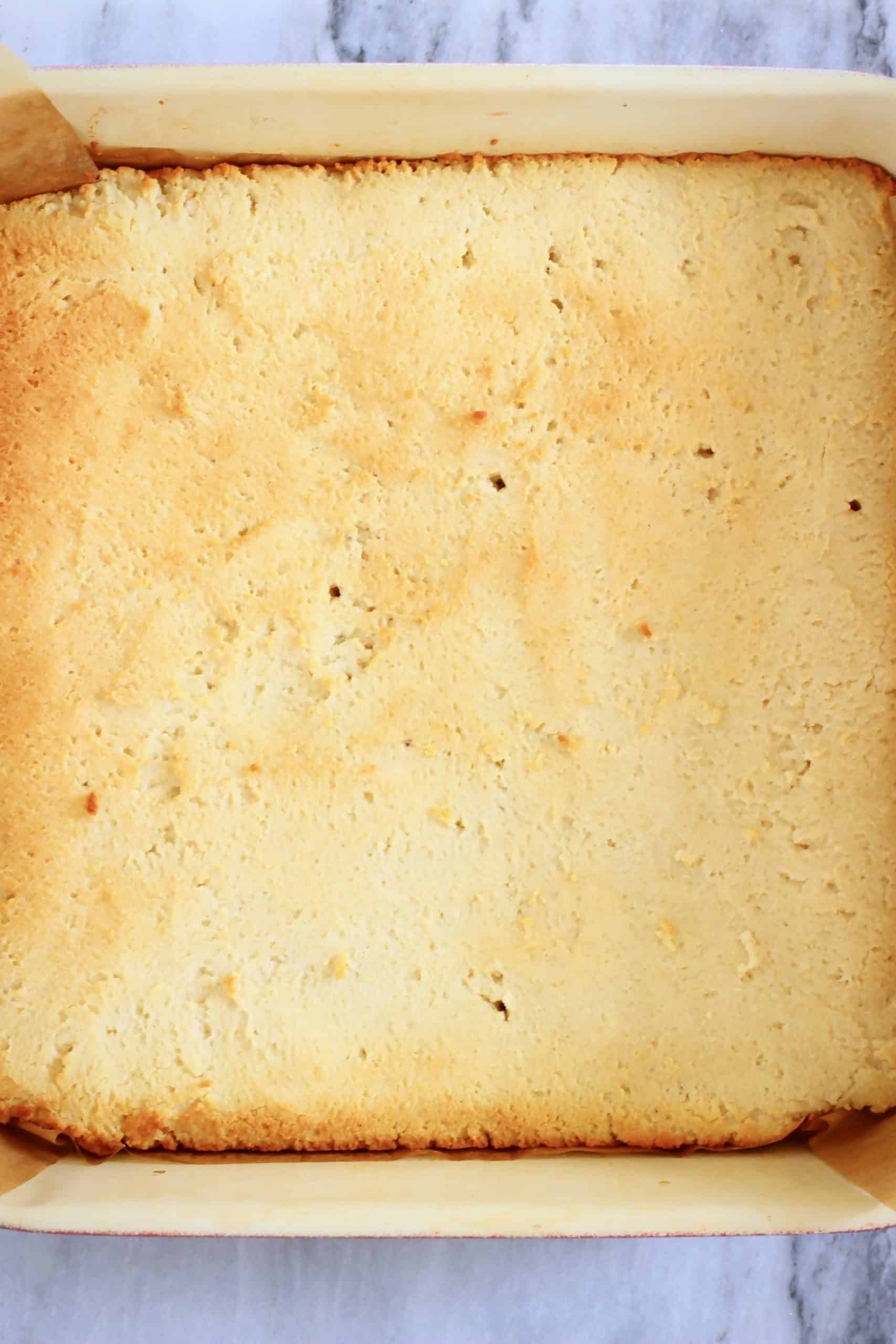 Baked gluten-free vegan tiramisu sponge cake in a square baking tin lined with baking paper
