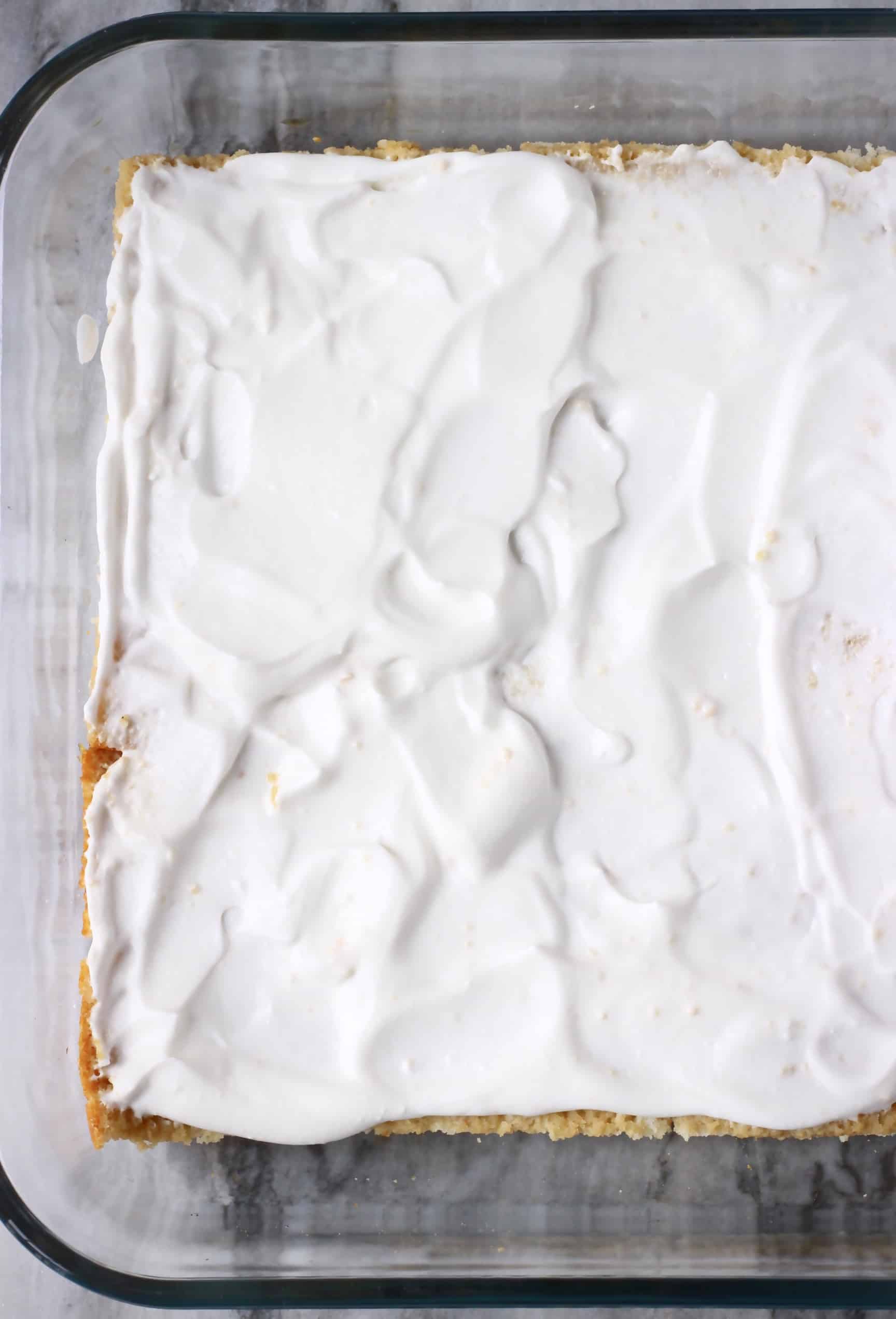 Photo of a large glass tray of tiramisu topped with white whipped cream taken from above