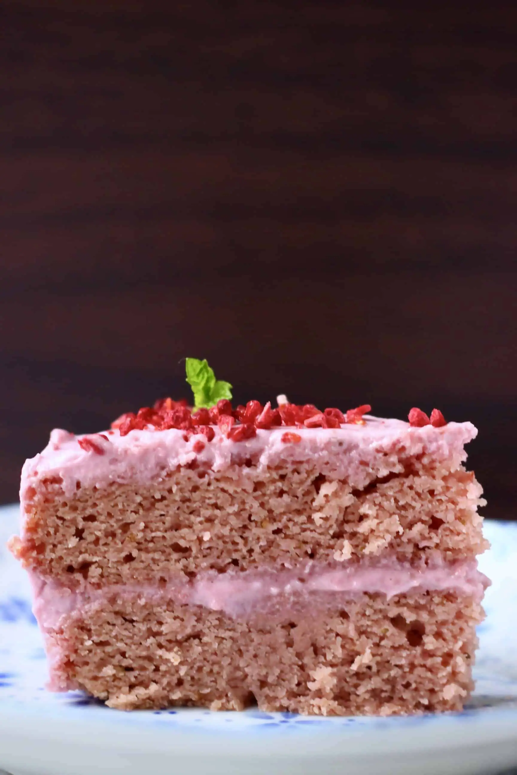 A slice of pink gluten-free vegan strawberry cake with pink strawberry frosting