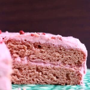 A sliced pink strawberry sponge layer cake with pink strawberry frosting