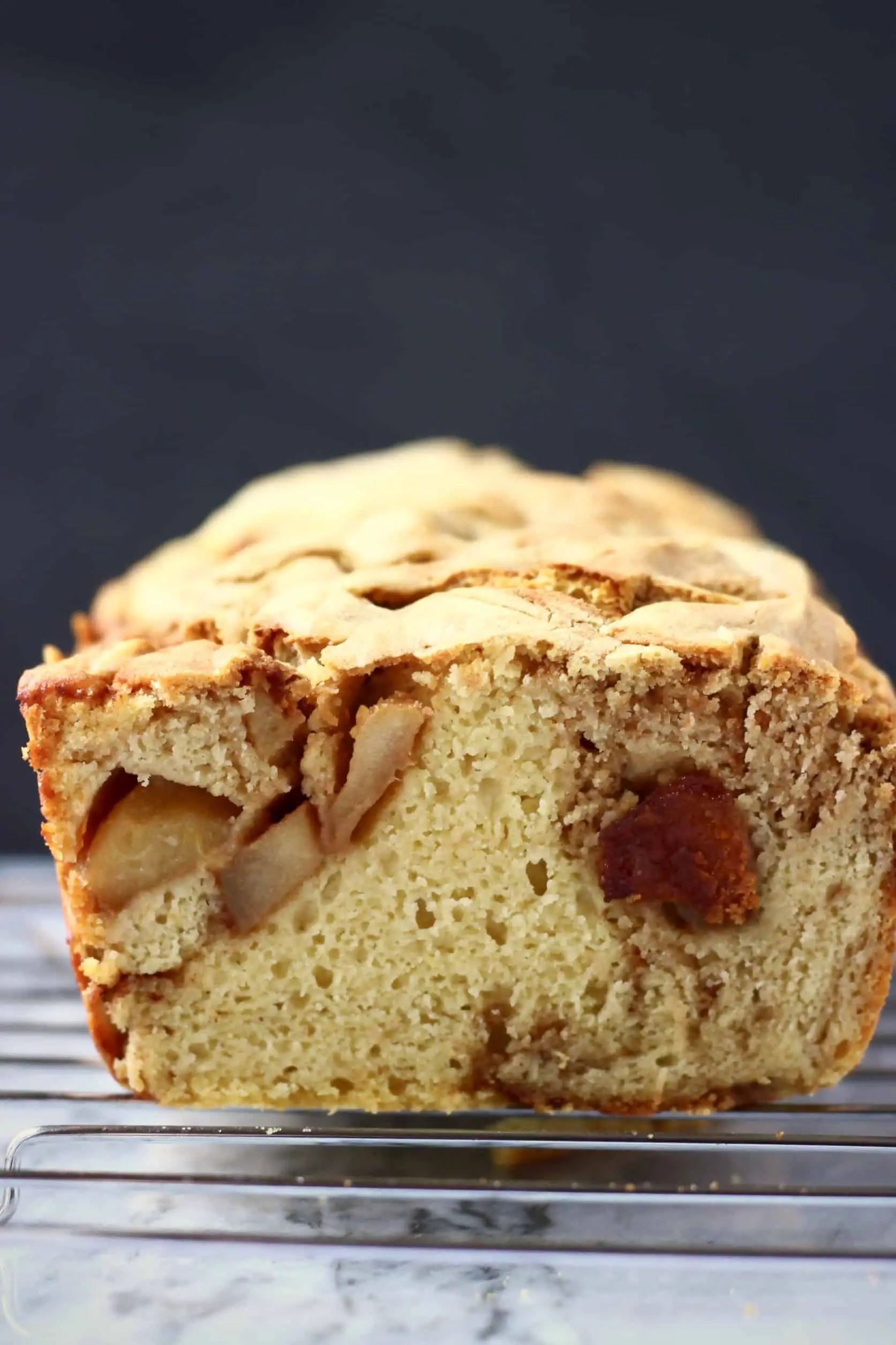 A sliced loaf of vegan apple bread on a wire rack