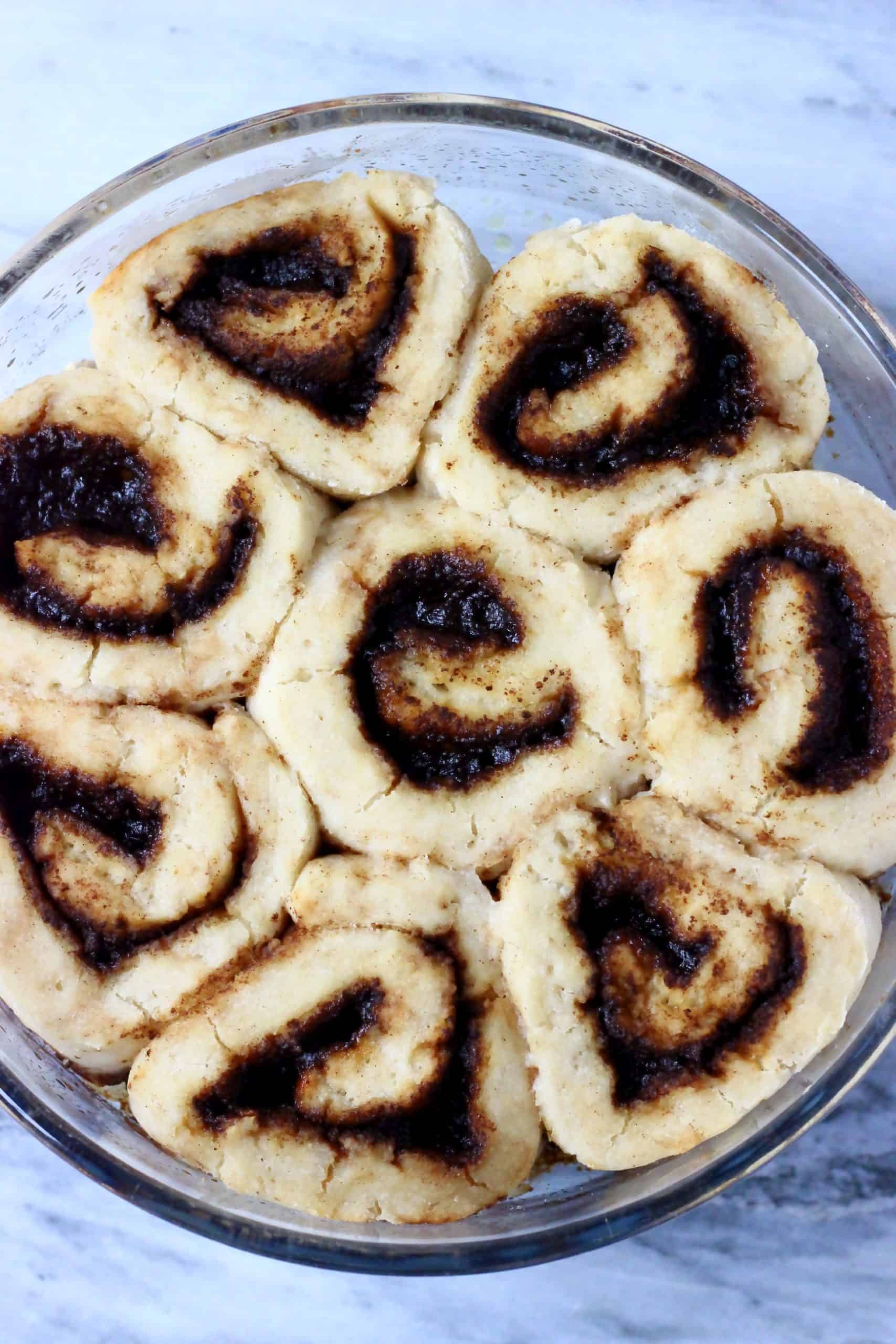 Eight gluten-free vegan cinnamon rolls in a round baking dish