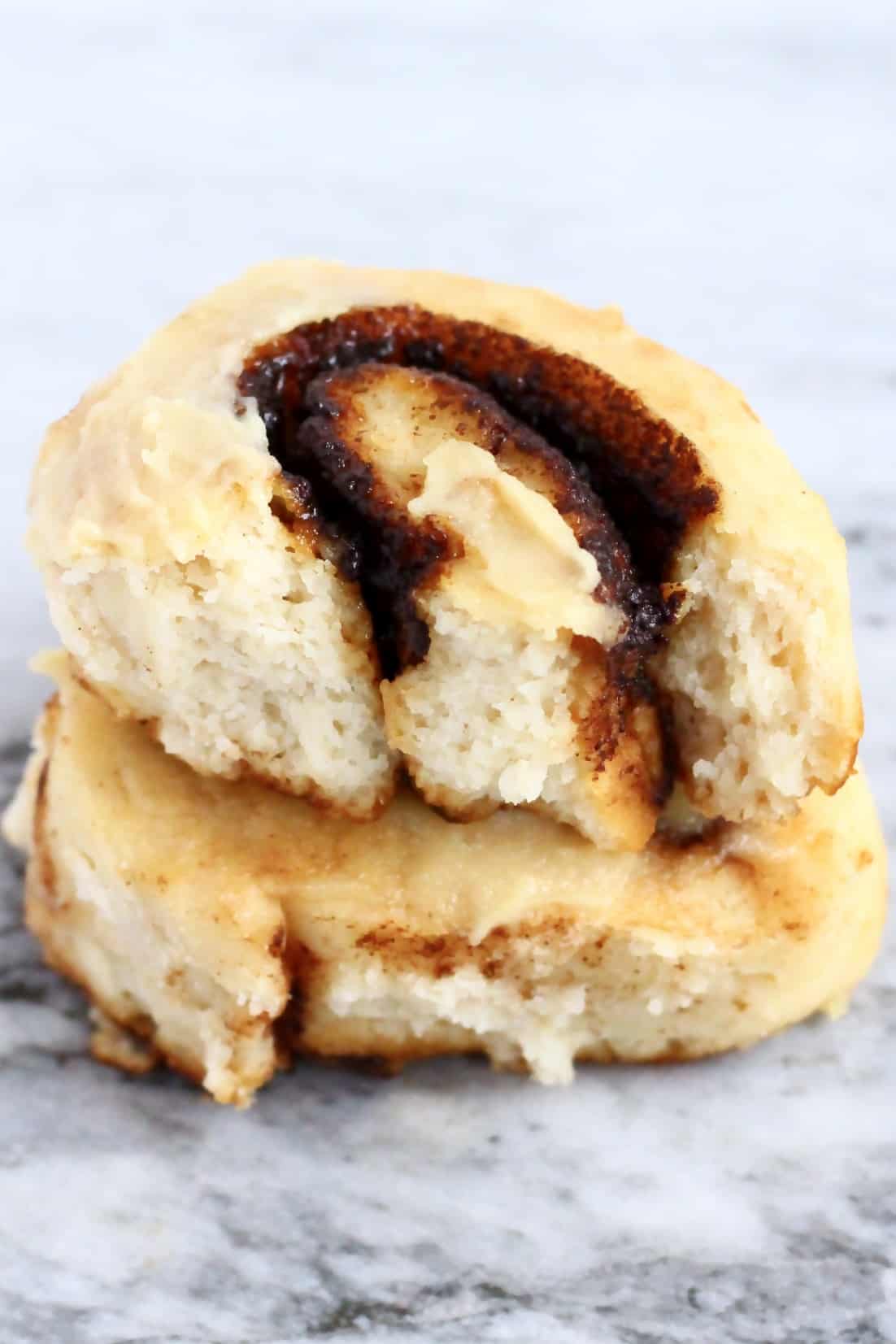 Two gluten-free vegan cinnamon rolls on top of each other, one cut in half