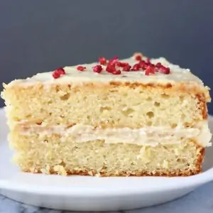 A slice of gluten-free vegan vanilla cake with buttercream on a plate