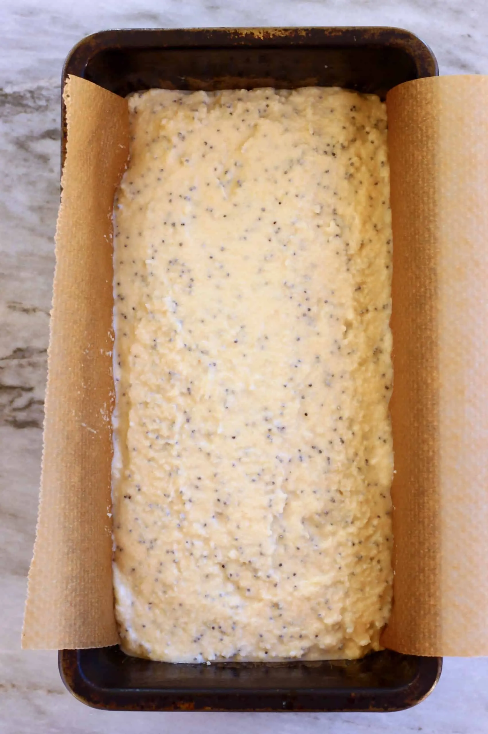 Gluten-free vegan lemon poppy seed cake batter in a loaf tin lined with baking paper