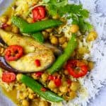 Eggplant, chickpea and vegetable curry with white rice on a grey plate against a marble background