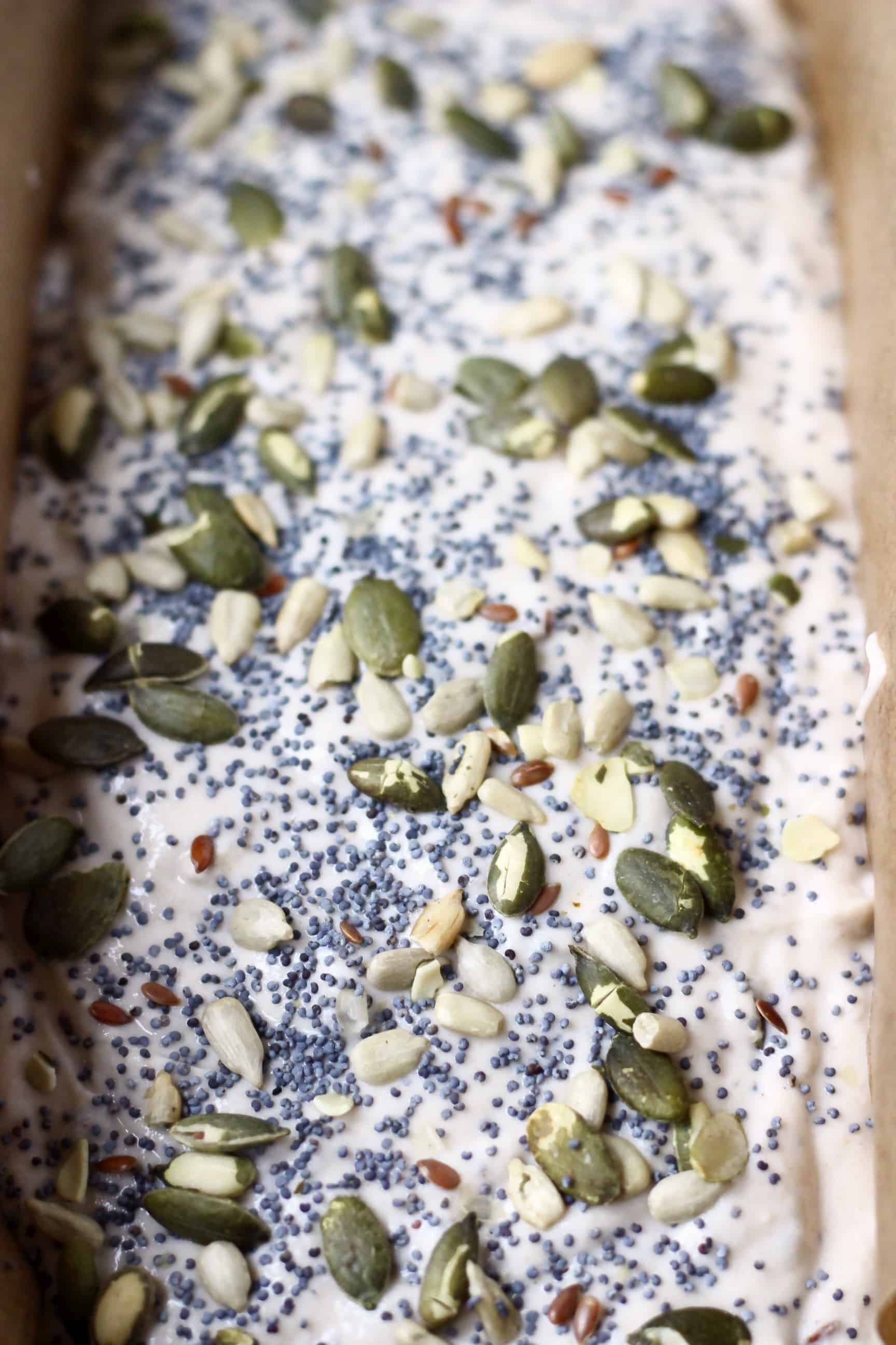 Gluten-Free Vegan Seeded Buckwheat Bread dough sprinkled with seeds in a loaf tin