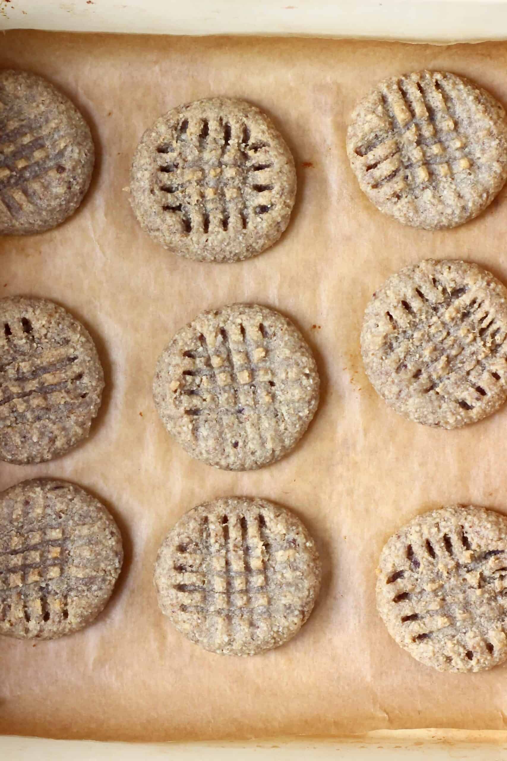 Nine gluten-free vegan peanut butter cookies on a baking tray lined with baking paper