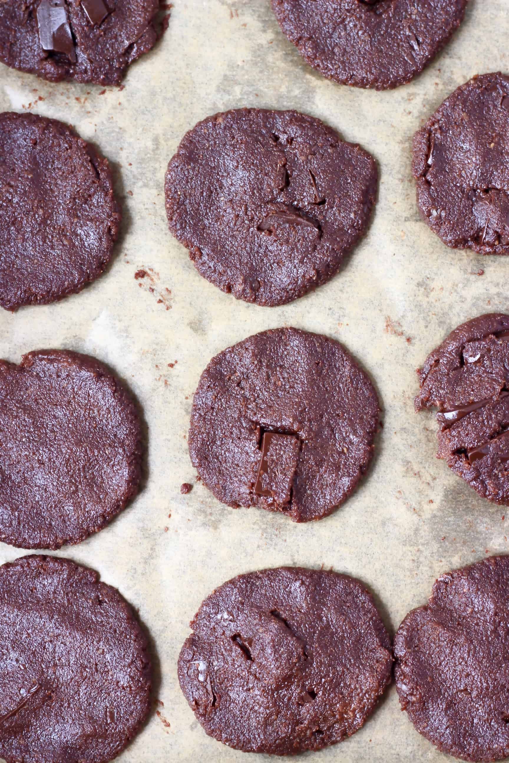 11 raw chocolate cookies on a sheet of brown baking paper