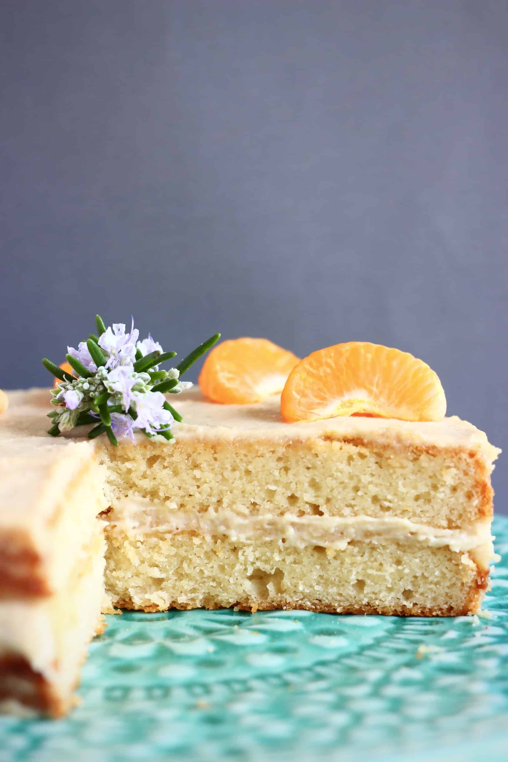 Sliced gluten-free vegan orange cake with buttercream topped with clementine segments