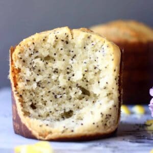 Un muffin de semillas de amapola de limón vegano sin gluten cortado por la mitad en una placa de mármol