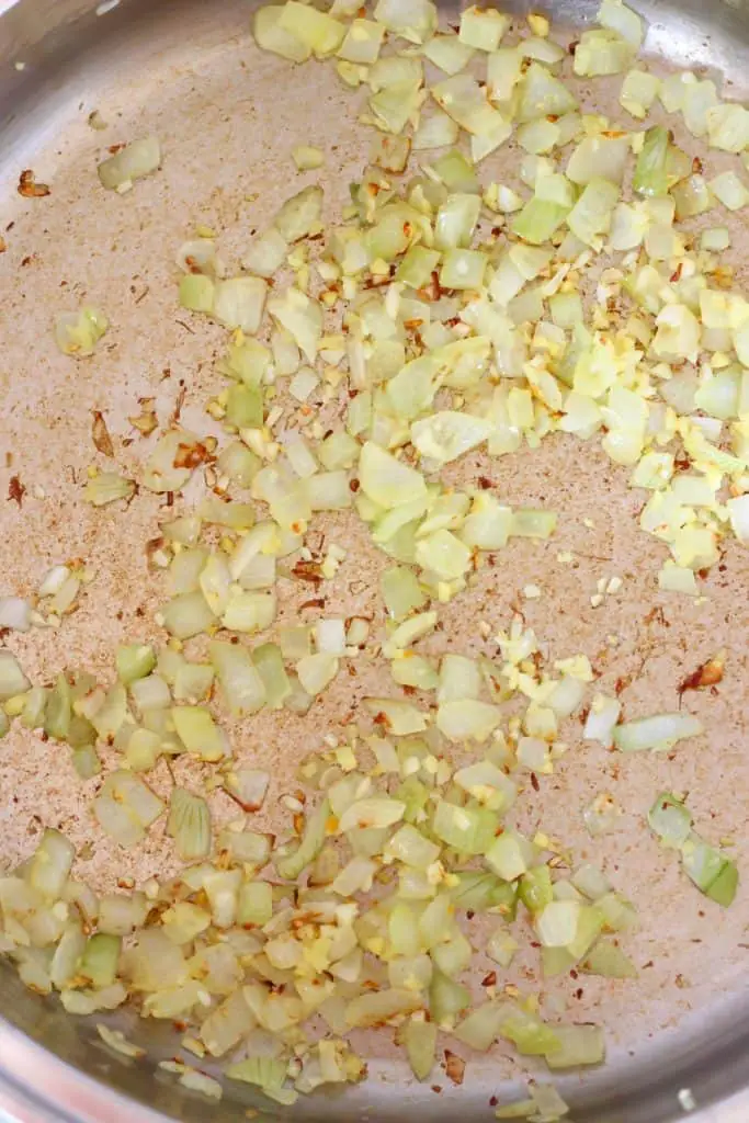 Diced onion, garlic and ginger being fried in a silver pan